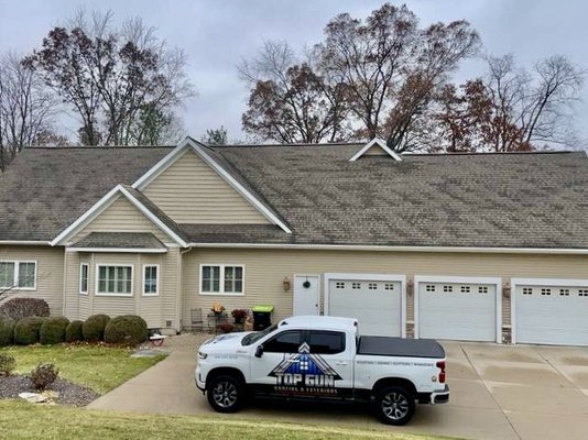 Top Gun Roofing & Exteriors team installing asphalt shingles on a residential roof in West Michigan